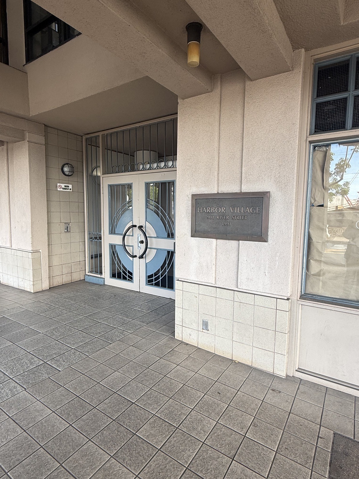 The entrance to a building with a sign that says "HARBOR VILLAGE".